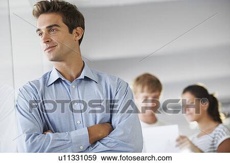 Stock Photo - Portrait of man with coworkers in background. Fotosearch