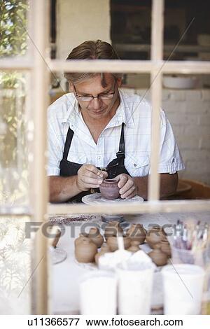 Stock Photo - Portrait of mature man decorating small vase. Fotosearch