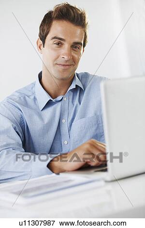 Portrait of mid adult man sitting at desk View Large Photo Image Stock Photo - Portrait of mid adult man sitting at desk. Fotosearch