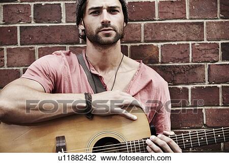 Stock Image - Portrait of musician against brick wall. Fotosearch