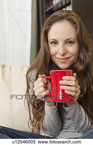 Stock Image - Portrait of smiling woman holding mug. Fotosearch