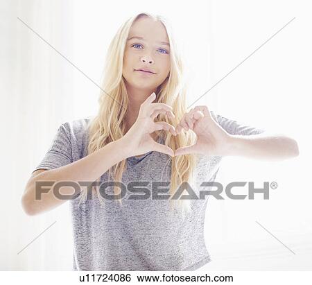 Stock Photograph - Portrait of teen (16-17) girl making heart shape with hands. Fotosearch