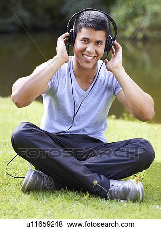 Stock Photo - Portrait of young man listening to music with headphones. Fotosearch