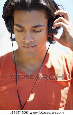 Portrait of young man listening to music with headphones View Large Photo Image Stock Photo - Portrait of young man listening to music with headphones. Fotosearch