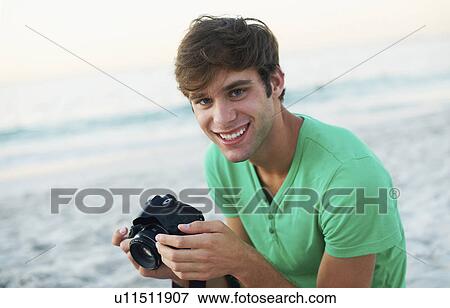Portrait of young man taking pictures at beach View Large Photo Image Stock Photo - Portrait of young man taking pictures at beach. Fotosearch
