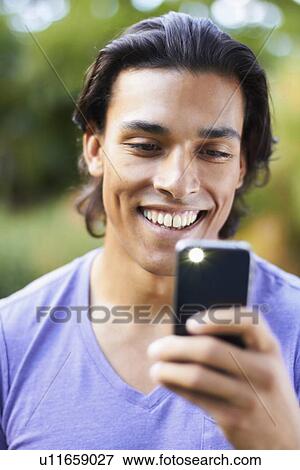 Stock Photo - Portrait of young man using mobile phone. Fotosearch