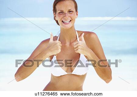 Stock Photography - Portrait of young woman giving thumbs up. Fotosearch