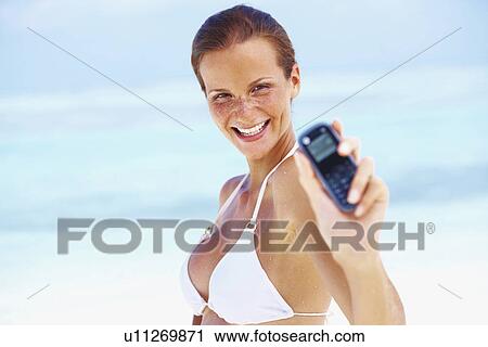 Stock Image - Portrait of young woman holding mobile phone. Fotosearch