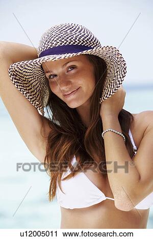 Stock Image - Portrait of young woman in bikini and straw hat. Fotosearch