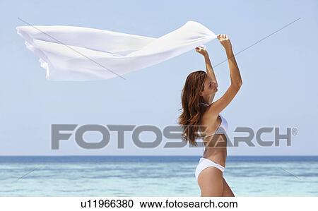 Stock Image - Portrait of young woman in bikini, arms raised. Fotosearch