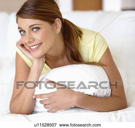 Stock Photo - Portrait of young woman lying on bed. Fotosearch