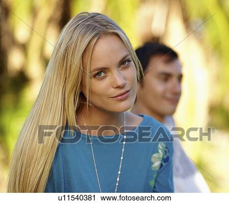Portrait of young woman, man in background View Large Photo Image Stock Image - Portrait of young woman, man in background. Fotosearch