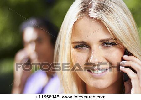 Portrait of young woman on phone, man in background View Large Photo Image Stock Photography - Portrait of young woman on phone, man in background. Fotosearch