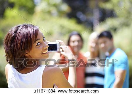 Picture - Portrait of young woman taking photo of people. Fotosearch