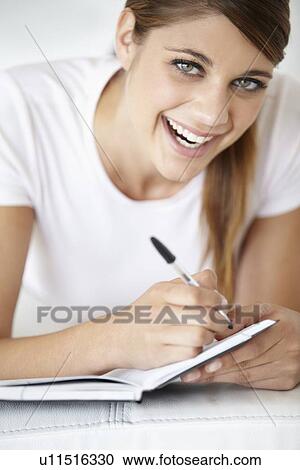 Portrait of young woman writing in notepad View Large Photo Image Stock Image - Portrait of young woman writing in notepad. Fotosearch