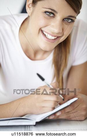 Stock Photograph - Portrait of young woman writing in notepad. Fotosearch