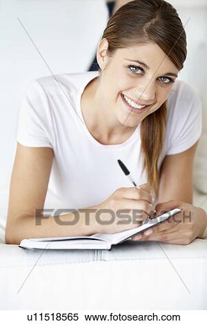 Portrait of young woman writing in notepad View Large Photo Image Stock Photography - Portrait of young woman writing in notepad. Fotosearch