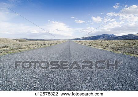 Stock Image - Road going through desolate landscape. Fotosearch