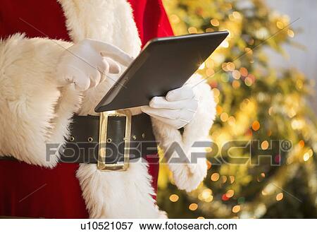 Santa claus holding digital tablet View Large Photo Image Stock Photo - Santa claus holding digital tablet. Fotosearch