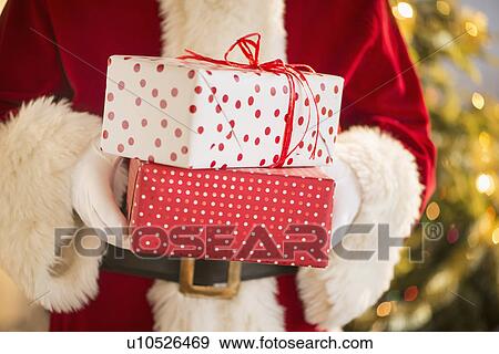 Stock Photo - Santa claus holding presents. Fotosearch