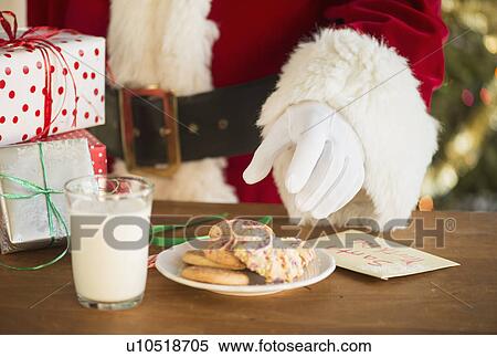 Stock Photography - Santa claus reaching for cookie. Fotosearch