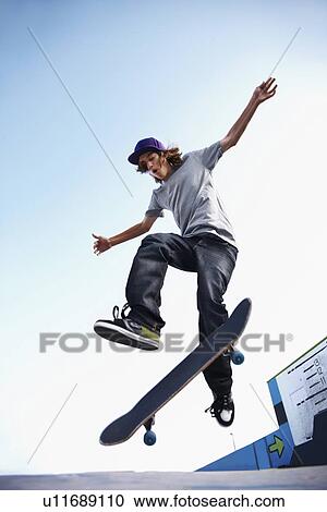 Skater performing jump in skateboard park View Large Photo Image Stock Image - Skater performing jump in skateboard park. Fotosearch
