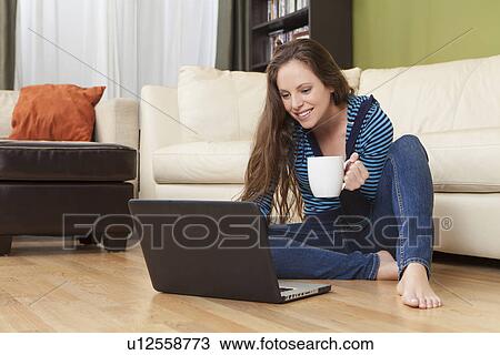 Smiling woman in living room using laptop View Large Photo Image Stock Image - Smiling woman in living room using laptop. Fotosearch