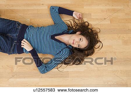 Stock Image - Smiling woman lying on floor, directly above. Fotosearch
