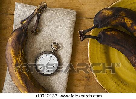 Stock Image - Still life with bananas and pocket watch. Fotosearch