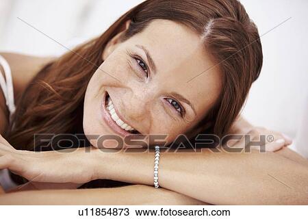 Stock Image - Studio portrait of woman smiling. Fotosearch