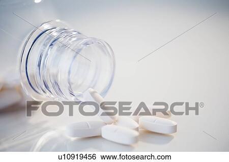 Stock Photograph - Studio Shot of white pills spilling out of bottle. Fotosearch