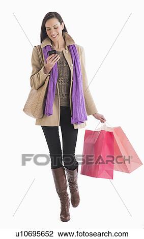 Studio shot of woman carrying shopping bags and text messaging View Large Photo Image Stock Image - Studio shot of woman carrying shopping bags and text messaging . Fotosearch