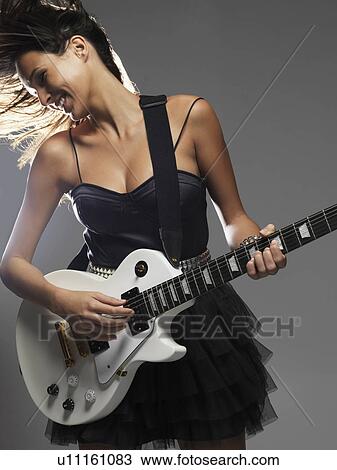 Stock Image - Studio shot of woman playing electric guitar. Fotosearch