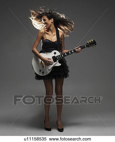 Stock Photography - Studio shot of woman playing electric guitar. Fotosearch