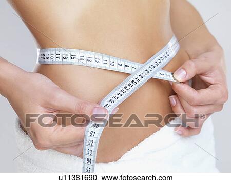Studio Shot, Woman measuring her waist with tape measure View Large Photo Image Stock Image - Studio Shot, Woman measuring her waist with tape measure. Fotosearch
