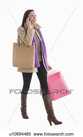 Stock Photography - Woman carrying shopping bags and talking on phone. Fotosearch
