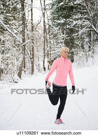 Stock Image - Woman exercising in winter forest. Fotosearch