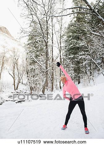 Stock Photo - Woman exercising in winter forest. Fotosearch