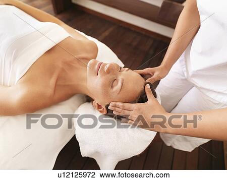 Stock Image - Woman getting facial massage in spa. Fotosearch