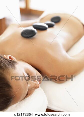 Picture - Woman getting hot stone therapy in spa. Fotosearch