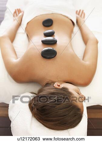 Stock Image - Woman getting hot stone therapy in spa. Fotosearch