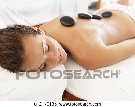 Stock Photography - Woman getting hot stone therapy in spa. Fotosearch