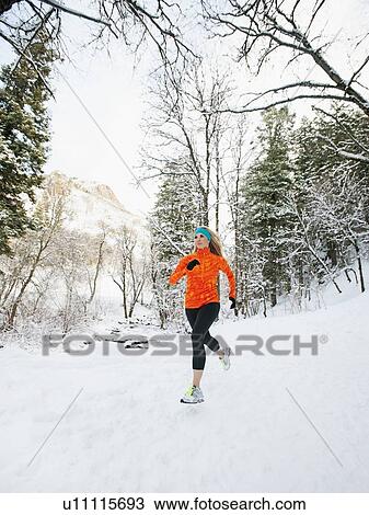 Stock Image - Woman jogging in winter forest. Fotosearch