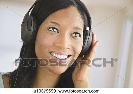 Stock Photo - Woman listening to music on headphones. Fotosearch