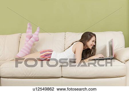 Woman lying on sofa with laptop View Large Photo Image Stock Image - Woman lying on sofa with laptop. Fotosearch