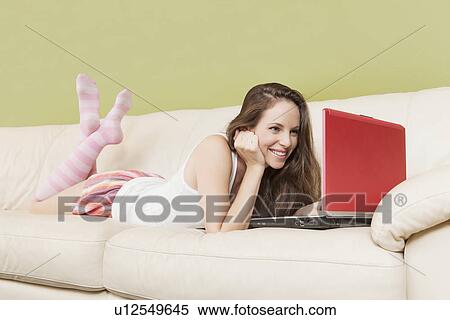 Woman lying on sofa with laptop View Large Photo Image Stock Photography - Woman lying on sofa with laptop. Fotosearch