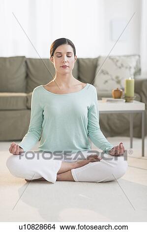 Woman meditating in living room View Large Photo Image Picture - Woman meditating in living room. Fotosearch