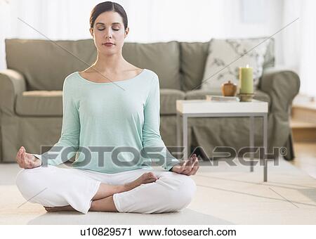 Woman meditating in living room View Large Photo Image Stock Image - Woman meditating in living room. Fotosearch