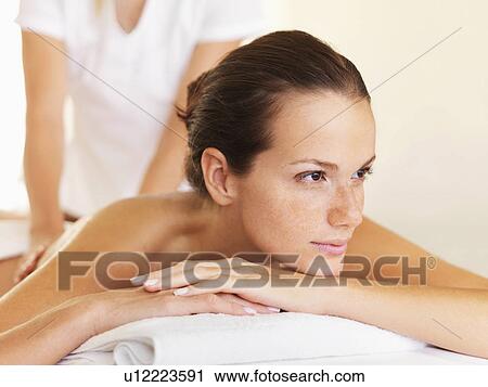 Stock Image - Woman relaxing while getting massage. Fotosearch