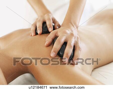 Stock Image - Woman relaxing while getting stone massage. Fotosearch